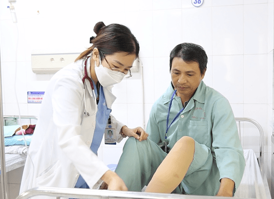 Bác sĩ kiểm tra chân cho người bệnh sau can thiệp suy giãn tĩnh mạch chi dưới