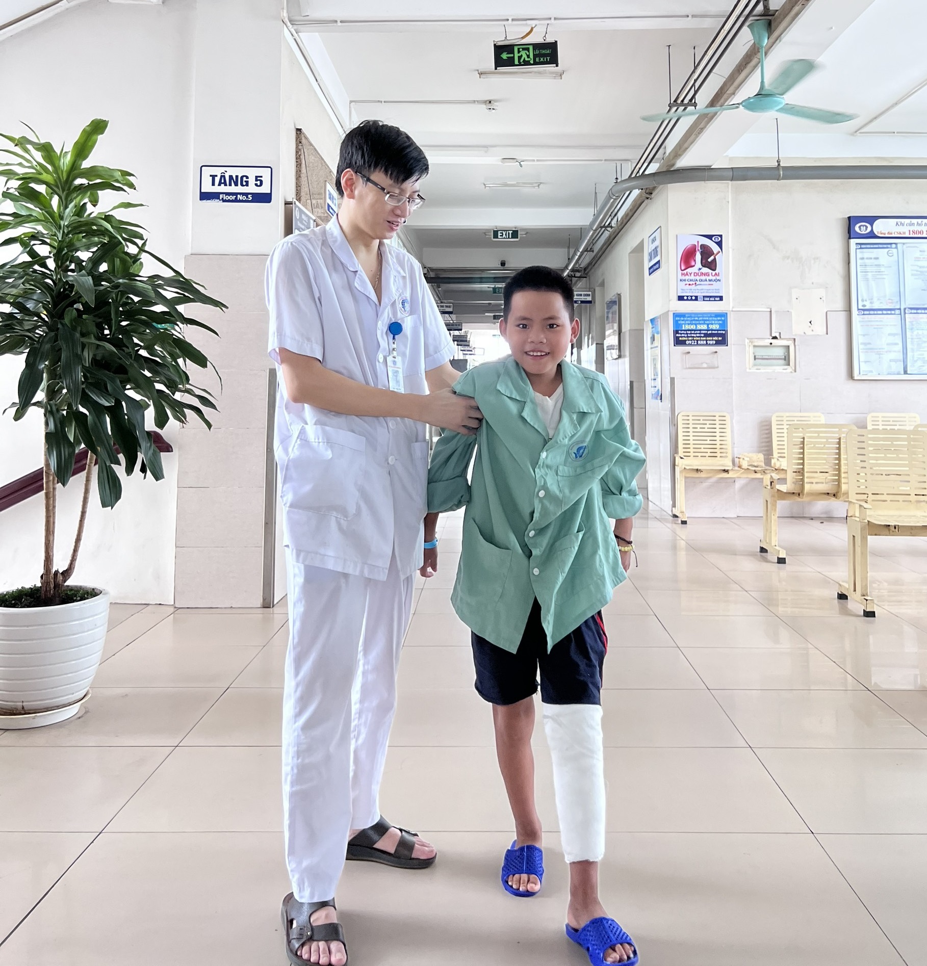 Bệnh nhi B.T.P vui vẻ tập đi lại dưới sự giúp đỡ của nhân viên y tế