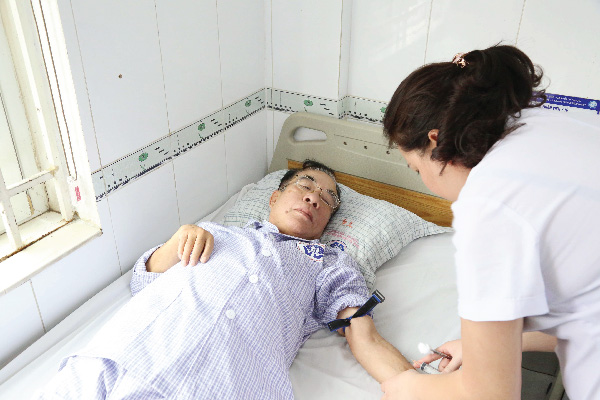 Hình ảnh điều dưỡng lấy máu làm xét nghiệm tại giường cho người bệnh bị đau đầu